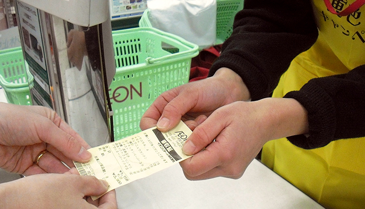 レジにて黄色いレシートを手渡される様子